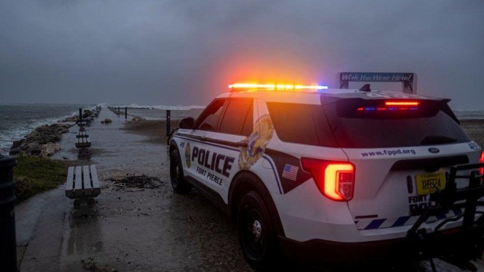 A police car blocks the entrance to the Inlet State Park before the expected arrival of Hurricane Nicole in Fort Pierce, Florida