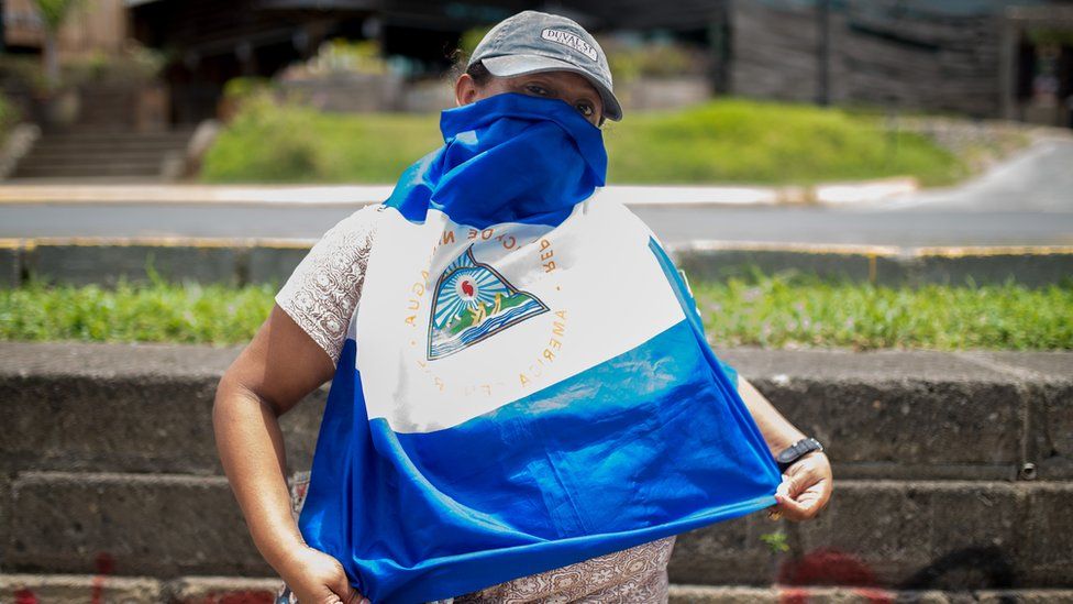 A protester in Nicaragua, who gives Claudia as a pseudonym, covers her face with a Nicaraguan flag
