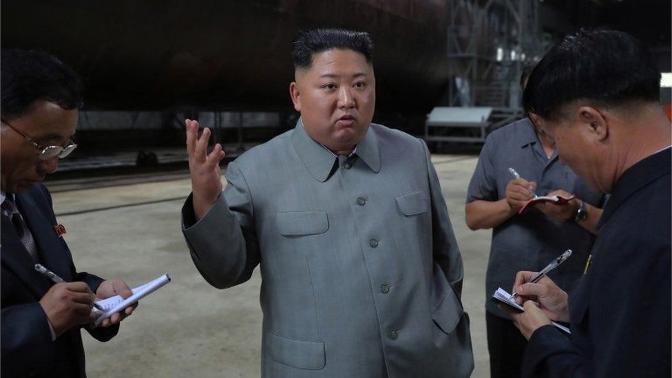 A photo released by the official North Korean Central News Agency (KCNA) on 23 July 2019 shows Kim Jong-Un (C), speaking to officials after making a round of the newly-laid down submarine at an undisclosed location in North Korea.