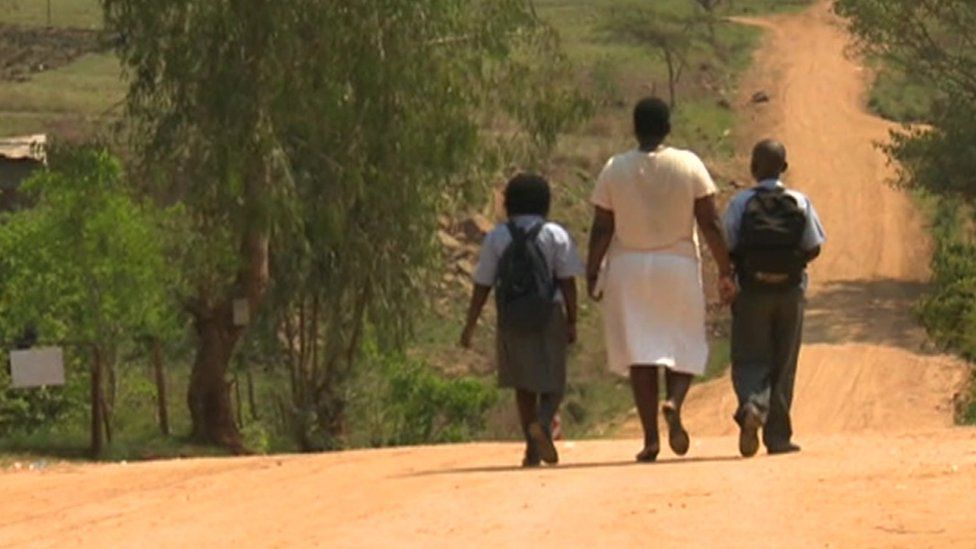 Woman and schoolchildren walking down the road