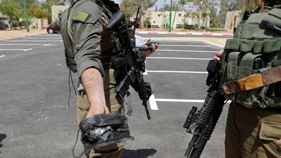 An Israeli soldier holds up an apparent missile fragment found in southern Israel (22 April 2021)