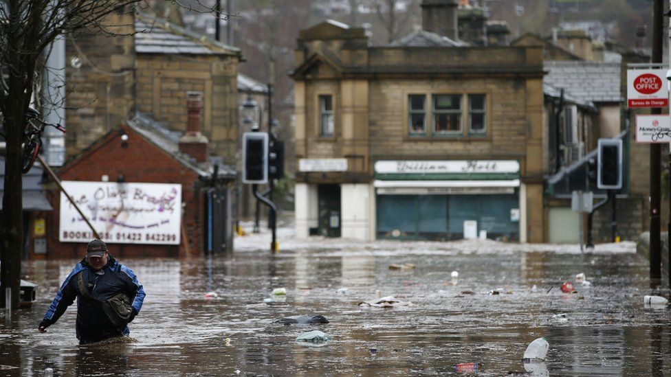 A man wades through flood waters at Hebden Bridge in West Yorkshire