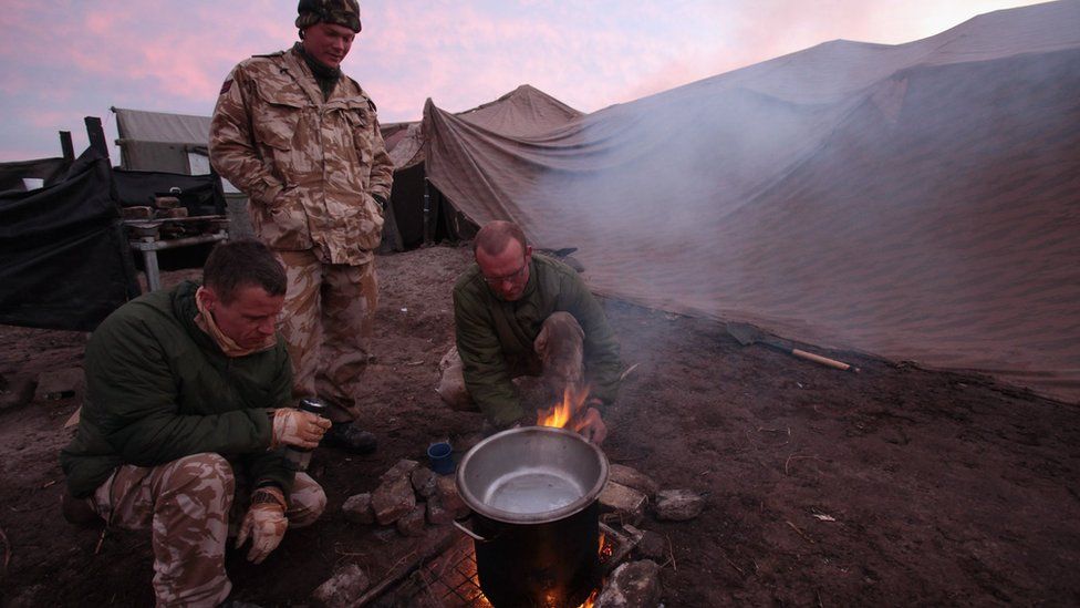 Soldiers cooking rations over a stove