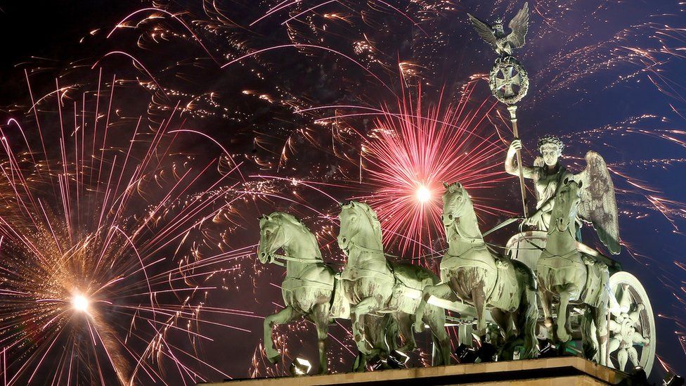 The Brandenburg Gate - a winged chariot rider with four horses - is seen in front of a sky filled with fireworks