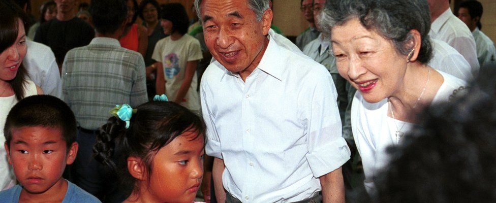 Emperor Akihito and Empress Michikos peak to local children on a visit to Niijima Island in the Izu island chain, south of Tokyo - July 2001