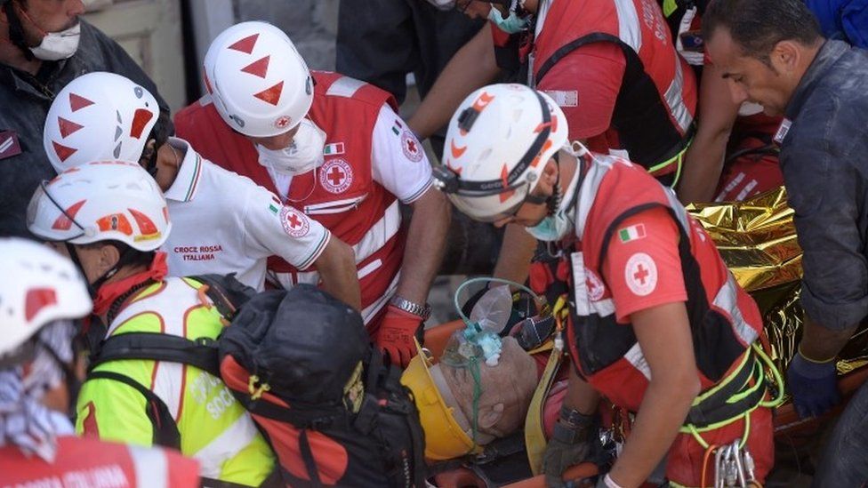 Rescue and emergency services personnel carry away a survivor on a stretcher in Amatrice (24 August 2016)