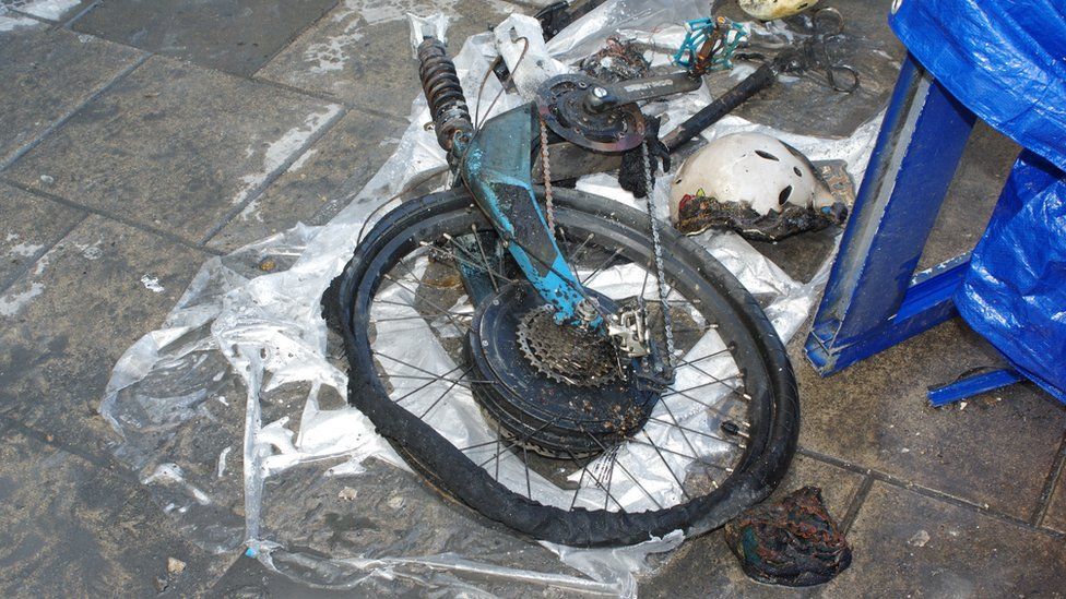 Image showing the burnt-out e-bike lying outside, with the tyre, saddle and helmet melted.