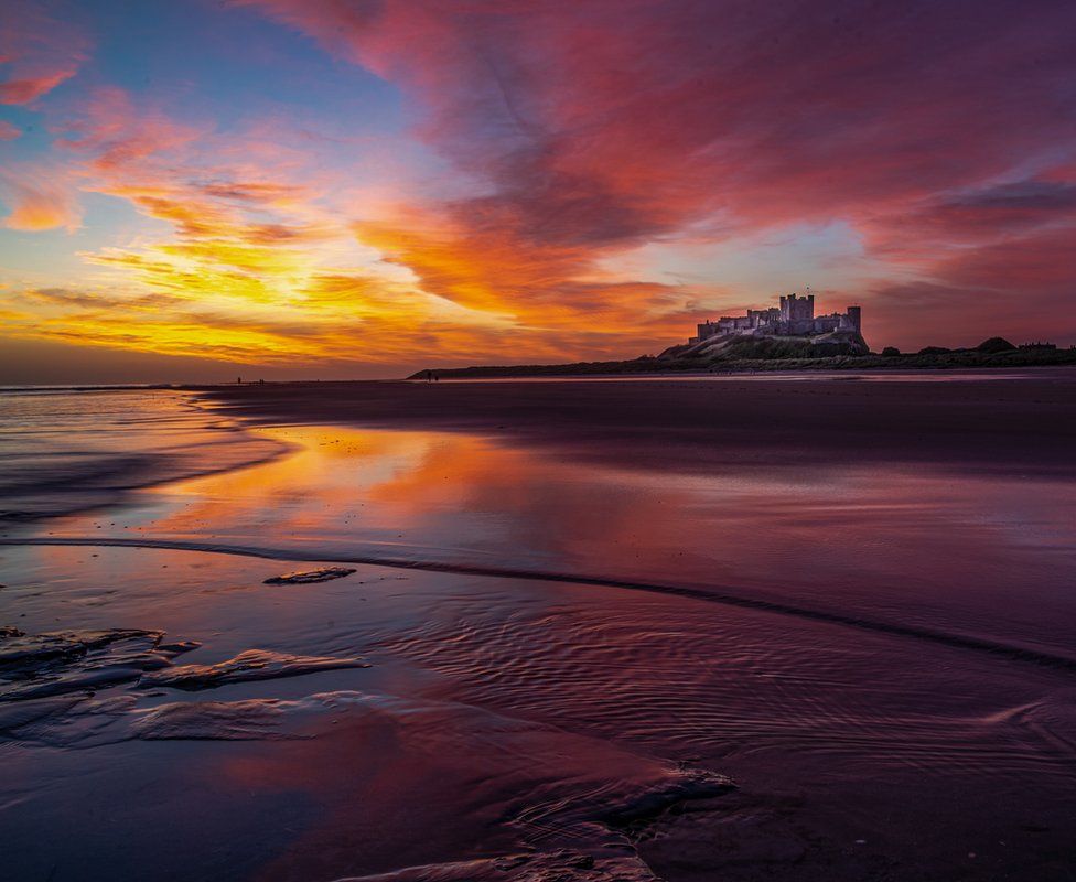 An orange, blue and purple sunset above Bamburgh Castle in England