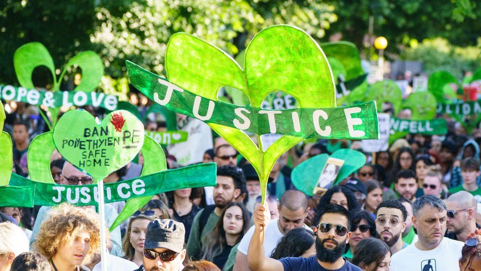 Hundreds of people march through west London armed with green banners saying "justice"