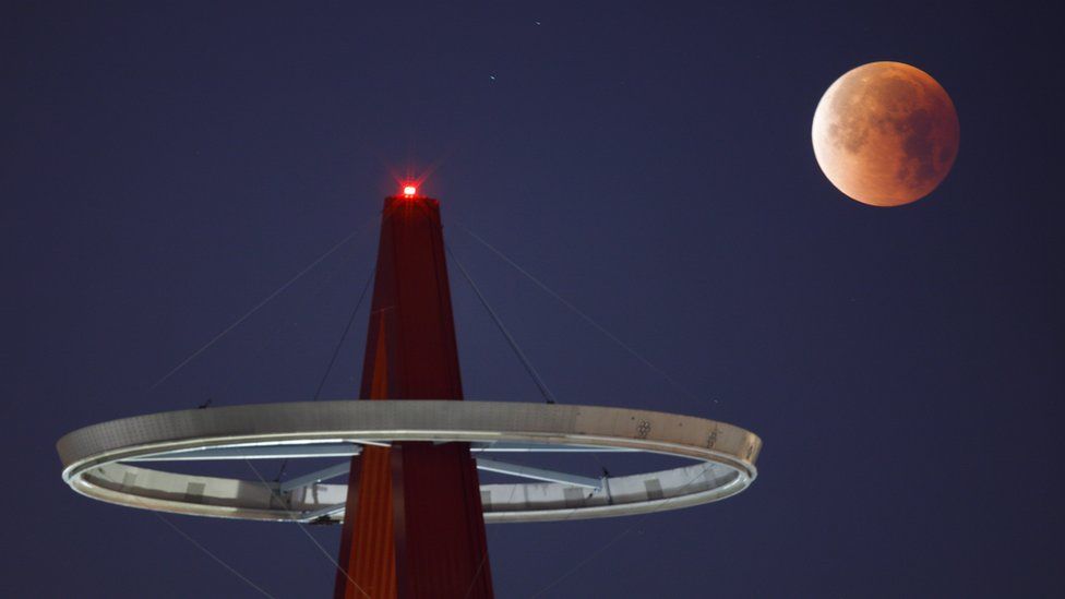 The super blue blood moon shines its blood red colours during a full eclipse above the Big A Sign of Angel Stadium in Anaheim, California