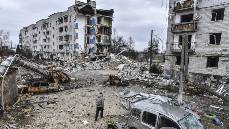 Man with backpack walks through ruined buildings in Ukraine