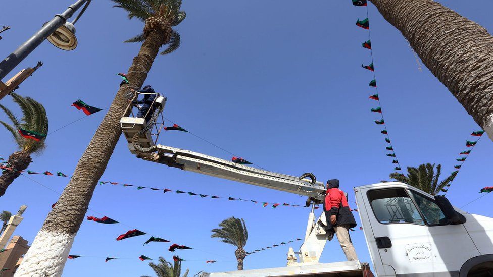 Workers hang flags at Tripoli's Martyrs' Square, on February 15, 2017, in prepping to mark the sixth anniversary of the start of the armed revolt against Gaddafi.