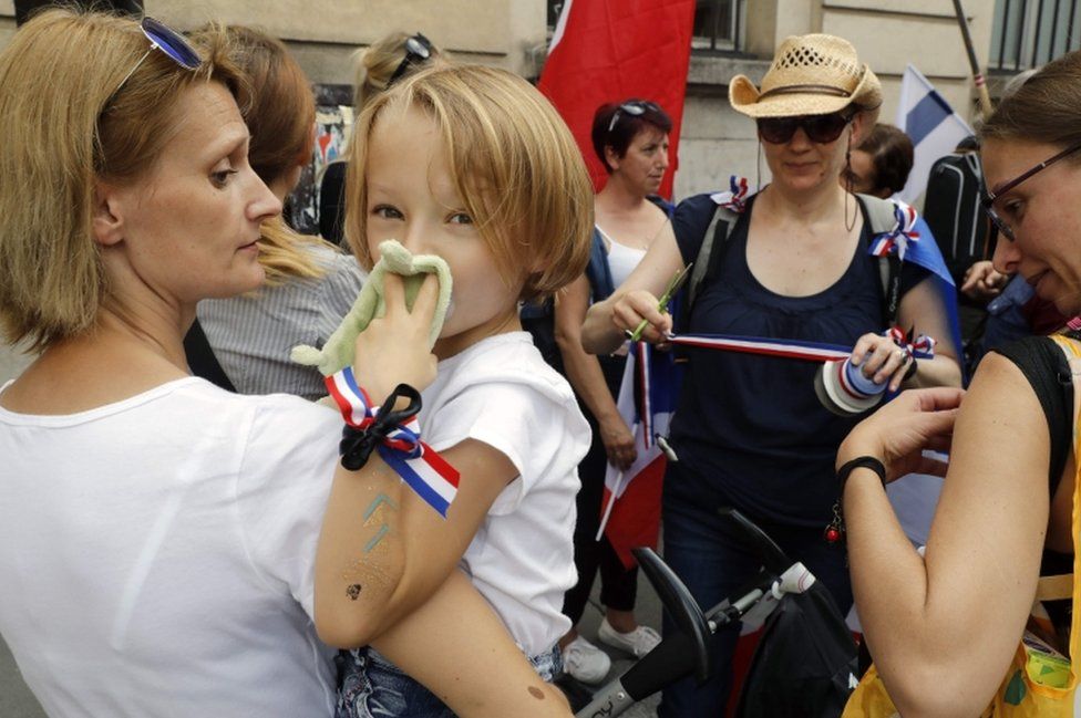 A woman holds her toddler at the "Military spouses are angry" demo in Paris on 26 August 2017.