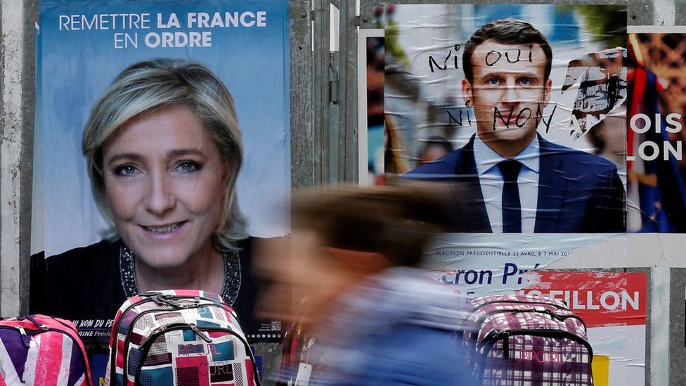 A woman walks past official posters of candidates for the 2017 French presidential election