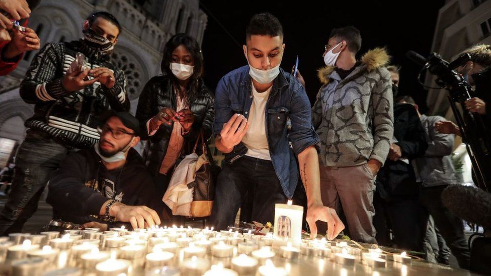 People lights candle outside the Notre-Dame de l'Assomption Basilica in Nice on October 29, 2020