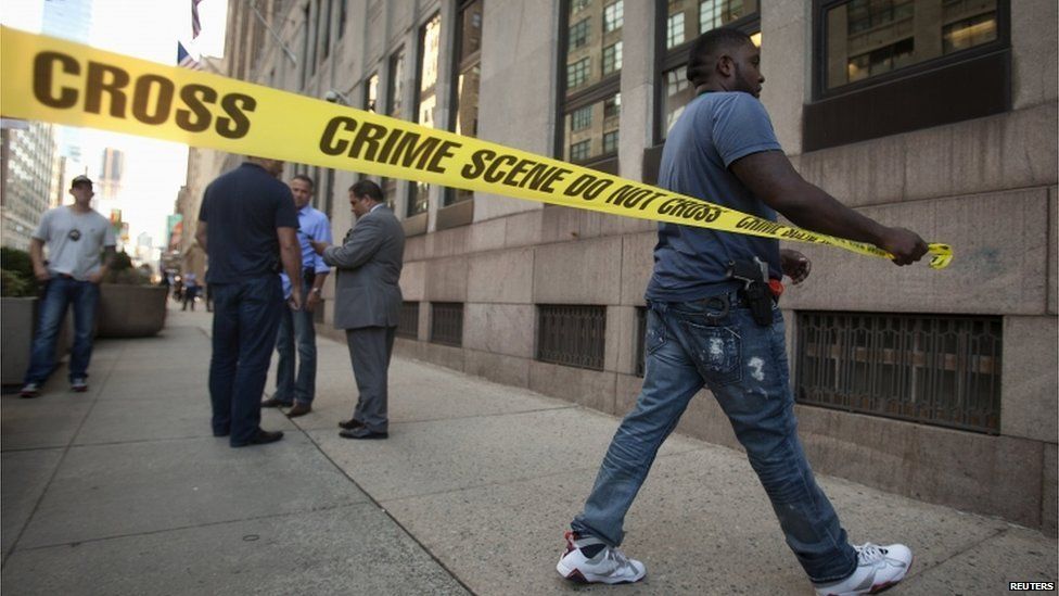 Police put up crime scene tape around the perimeter of a shooting scene outside of a federal building in the Manhattan borough of New York, on 21 August 2015.