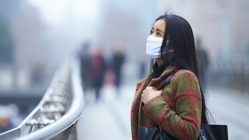 Woman wearing face mask in polluted city