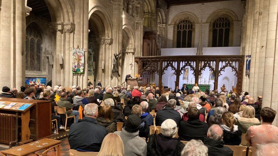 People gather inside Priory Church for a question and answer session