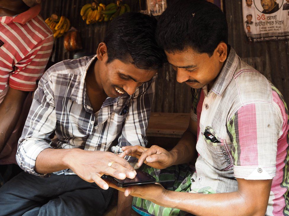 Bangladesh, 2014. Two men look at their phone