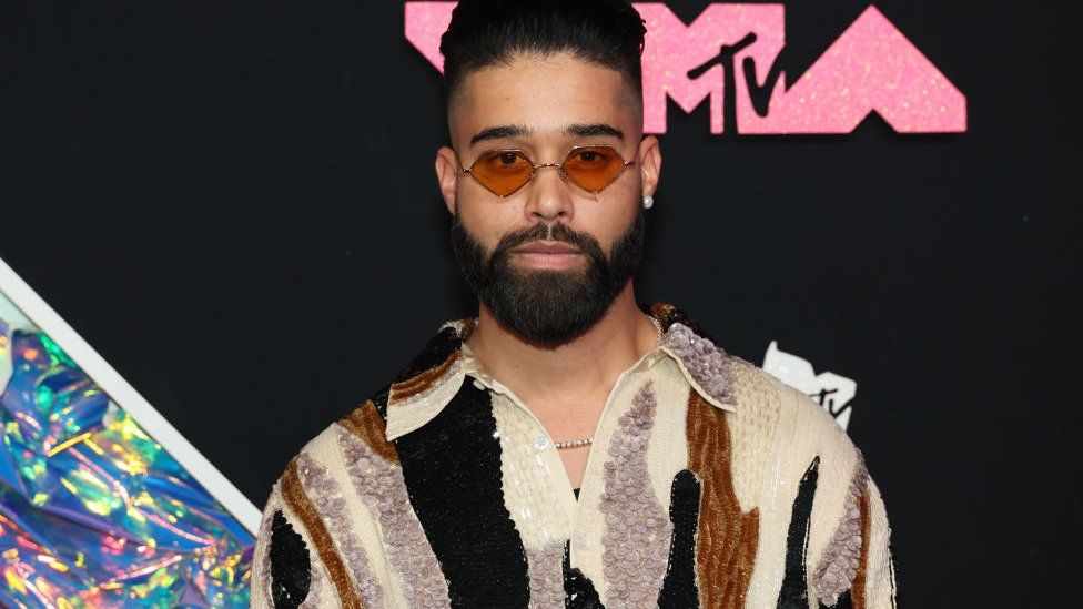 AP Dhillon at the MTV EMAs, he is wearing sunglasses and a sparkly patterned shirt.