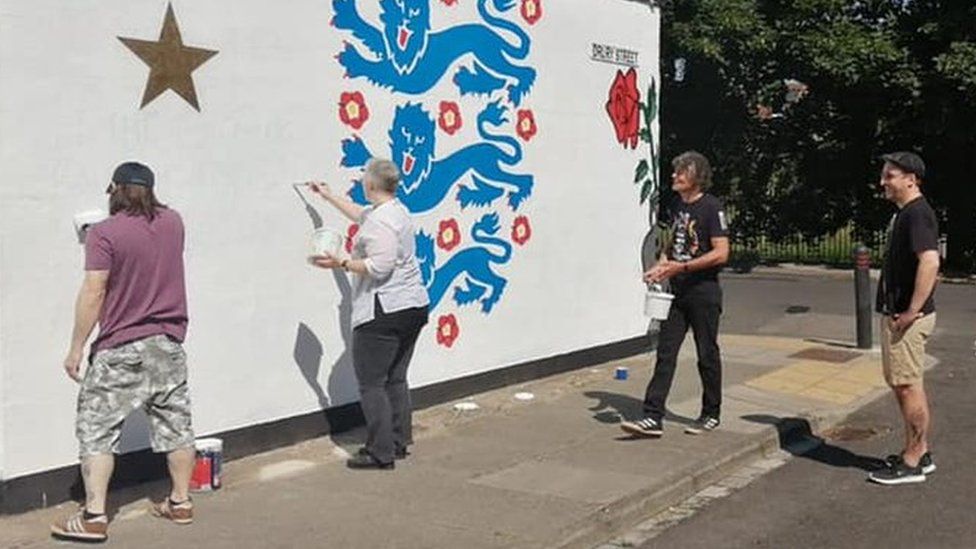 People painting over the graffiti