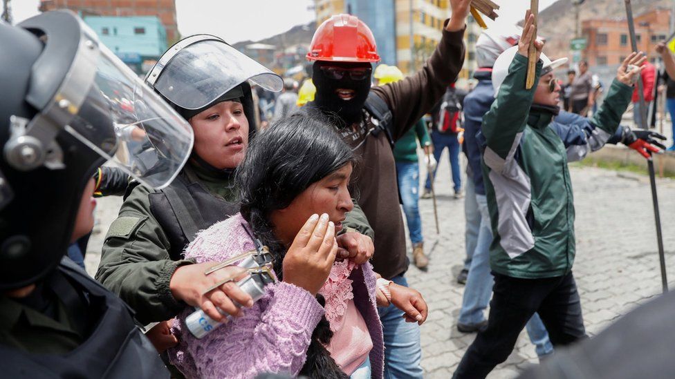 Members of the security forces detain a woman during clashes between supporters of Evo Morales and opposition supporters in La Paz, Bolivia, 11 November, 2019.
