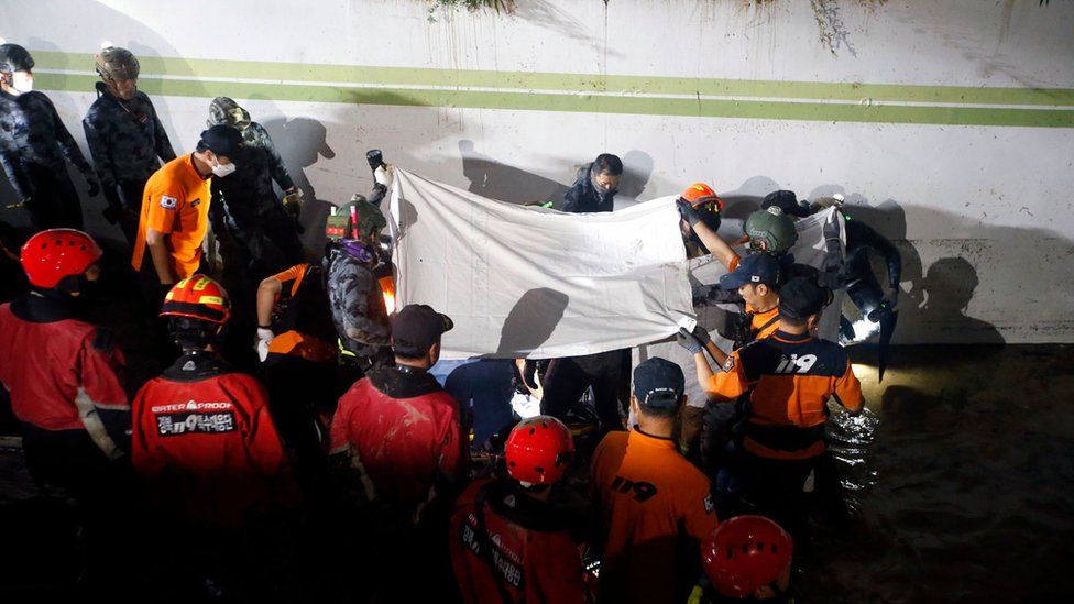 Crews remove a body - covered by a white sheet -from the submerged basement car park