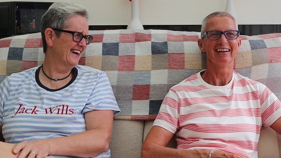 Foster carers Liz and Caroline sat on a sofa