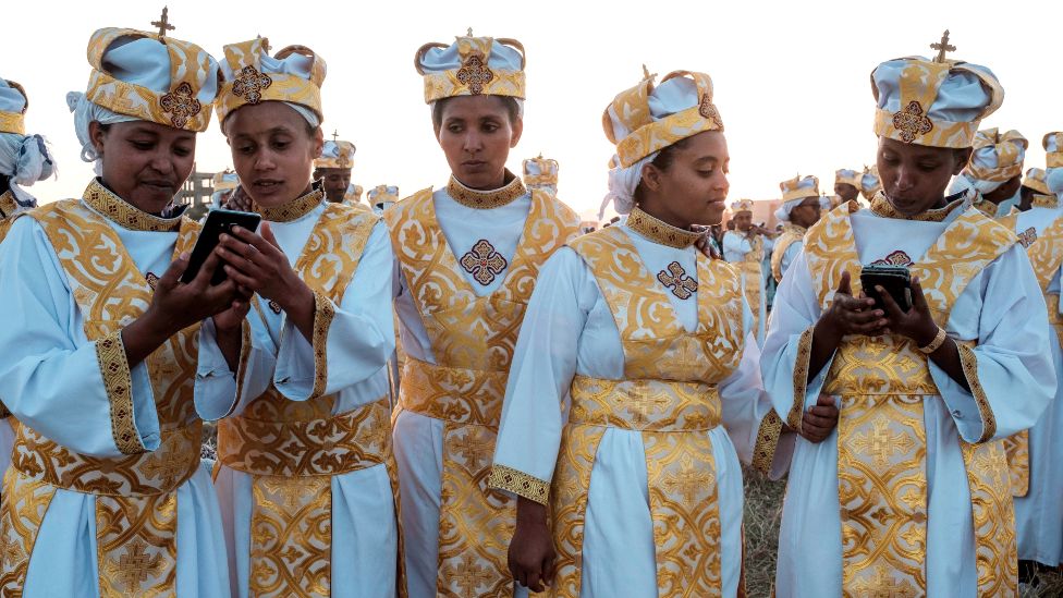 Эфиопские православные христиане используют смартфоны во время религиозного праздника в Аддис-Абебе, 2019 г.