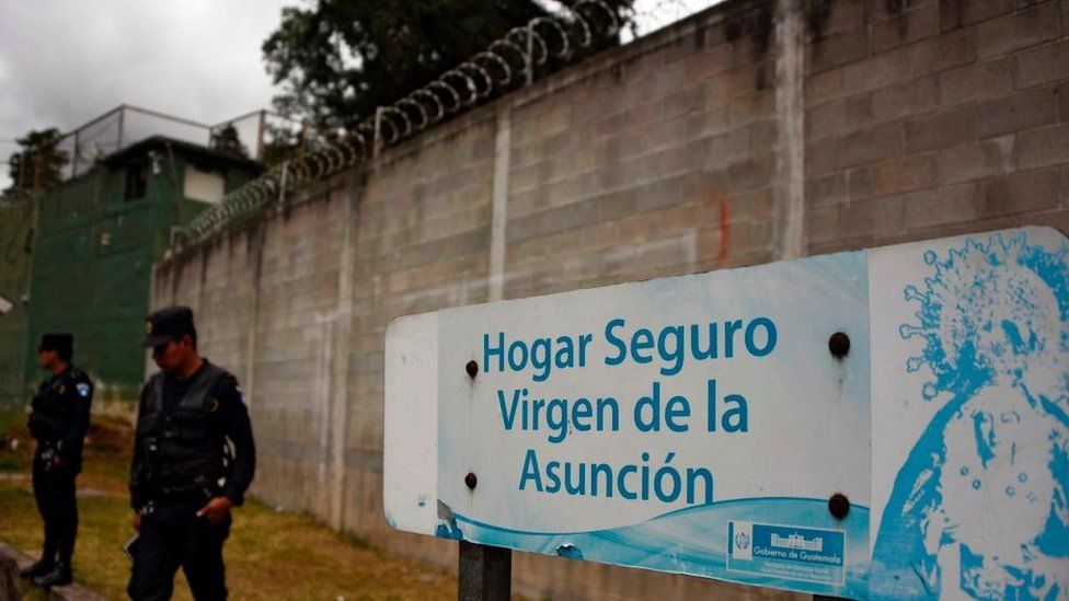 Police agents stand guard next to a sign that reads "Sage home Virgen de la Asuncion" at the children's shelter entrance after 40 girls died during a fire on March 8, in San Jose Pinula, about 10 kilometres east of Guatemala City on March 15, 2017.