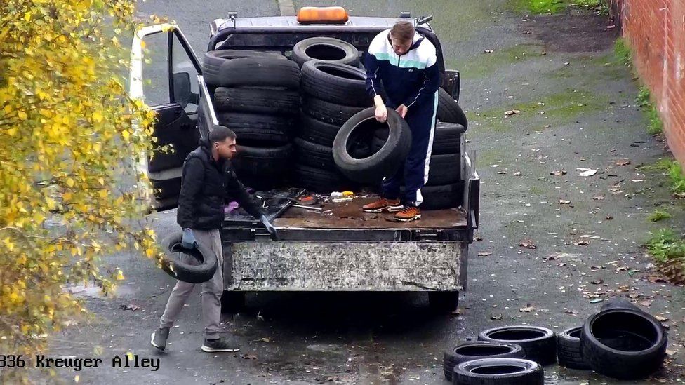 CCTV camera still of two men on a truck loaded with tyres, with other tyres on the ground