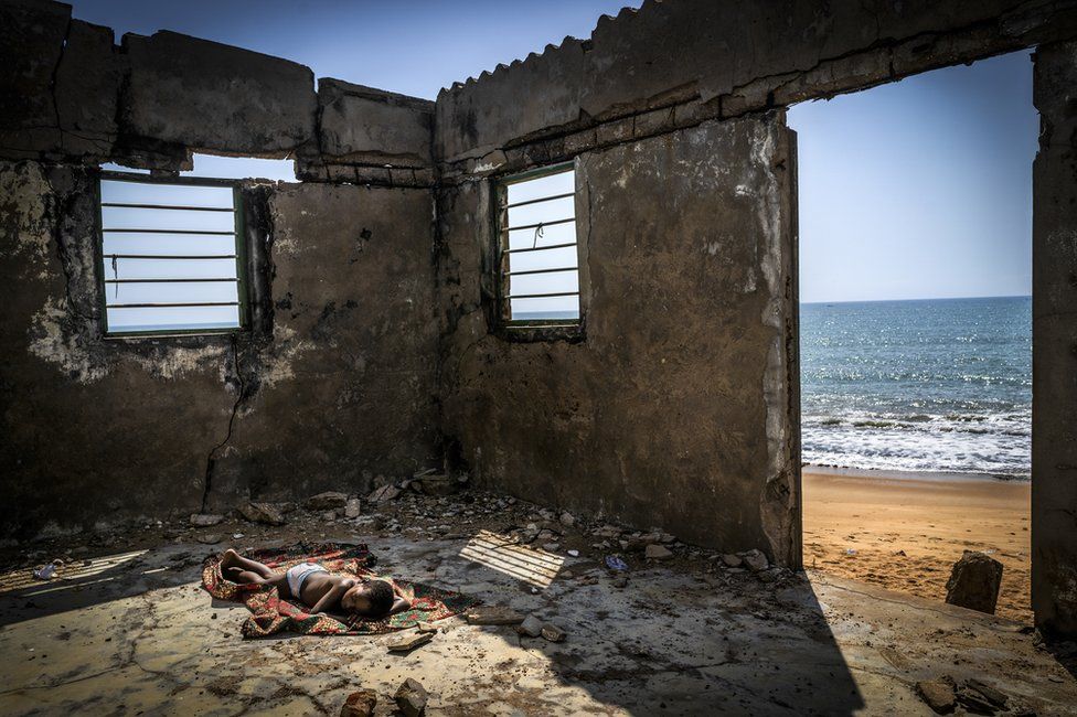A child sleeps inside a derelict building on a beach in Ghana in 2019