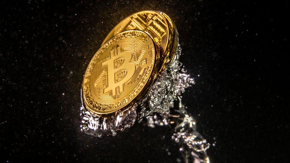A stock image of coins bearing the bitcoin logo - an illustrative reification of the cryptocurrency - dropped into water