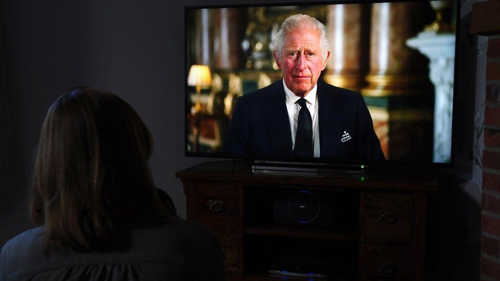 Person watches King Charles address the nation