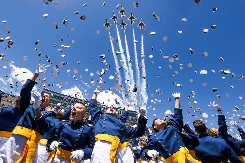Air Force Academy cadets toss their hats in the air as the Air Force Thunderbirds fly over at the conclusion of the graduation ceremony for the class of 2022 at Falcon Stadium in Colorado Springs, Colorado, on 25 May 2022