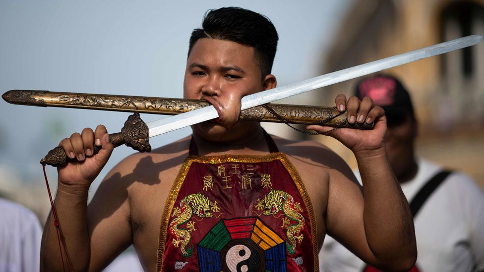 A performer gores his face with a sheath and a sword