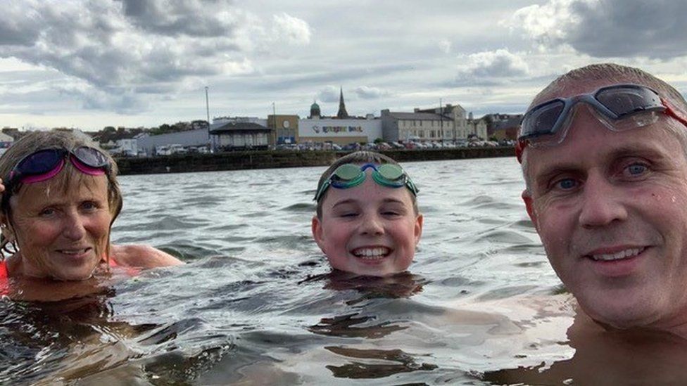 Joshua Collacott swimming with his father (right) and grandmother (left)