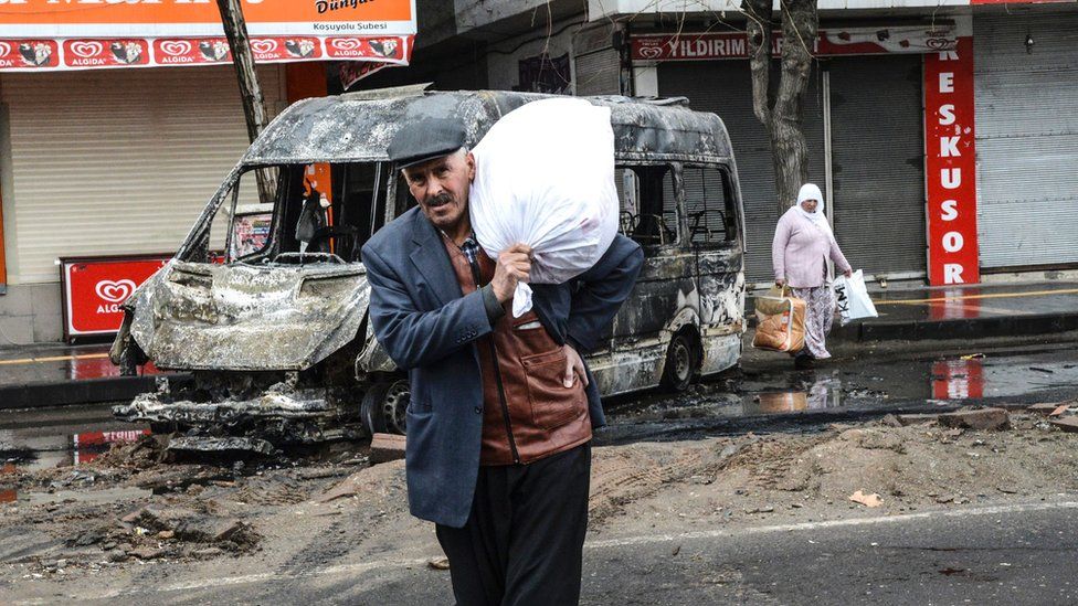 People carry their belongings as they leave their houses during clashes in central Diyarbakir on 15 March 2016.