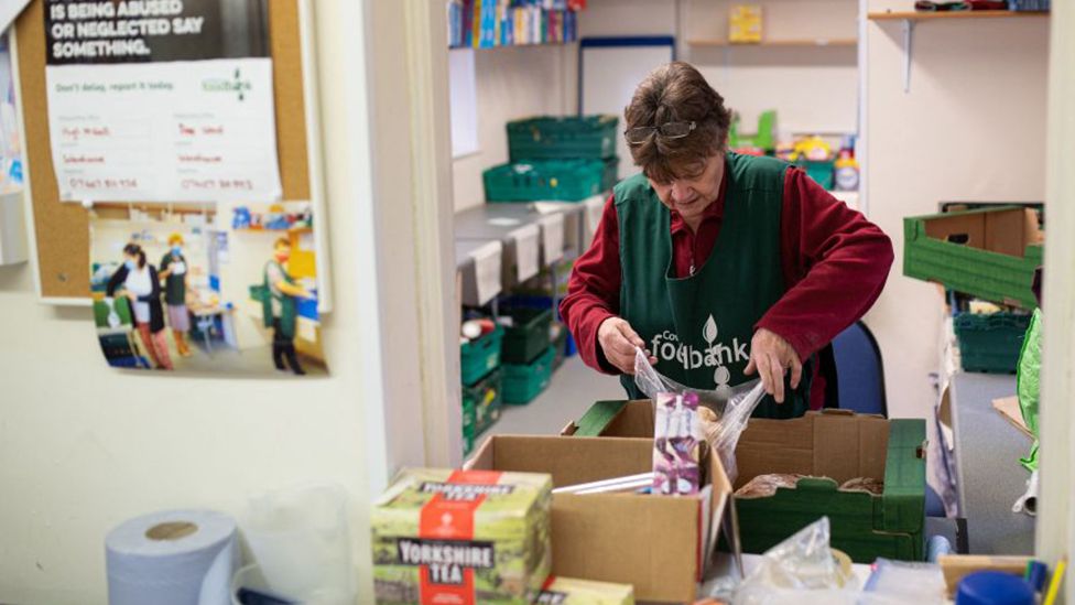 A woman fills a bag at a food bank in Coventry