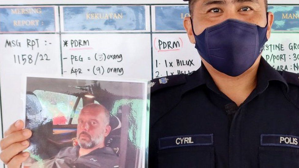 Mersing district police chief Cyril Edward shows the pictures of British man Adrian Peter Chesters and French woman Alexia Alexandra Molina, who were found safe after drifting at sea for two and a half days