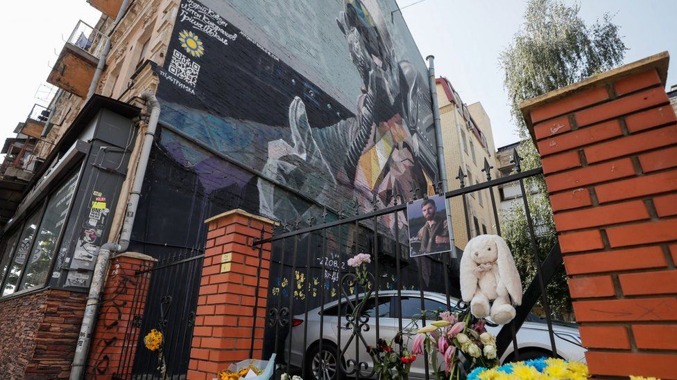 Andrii Pilshchykov's photo hangs over flowers next to the Ghost of Kyiv mural in the Ukrainian capital. Photo: 29 August 2023