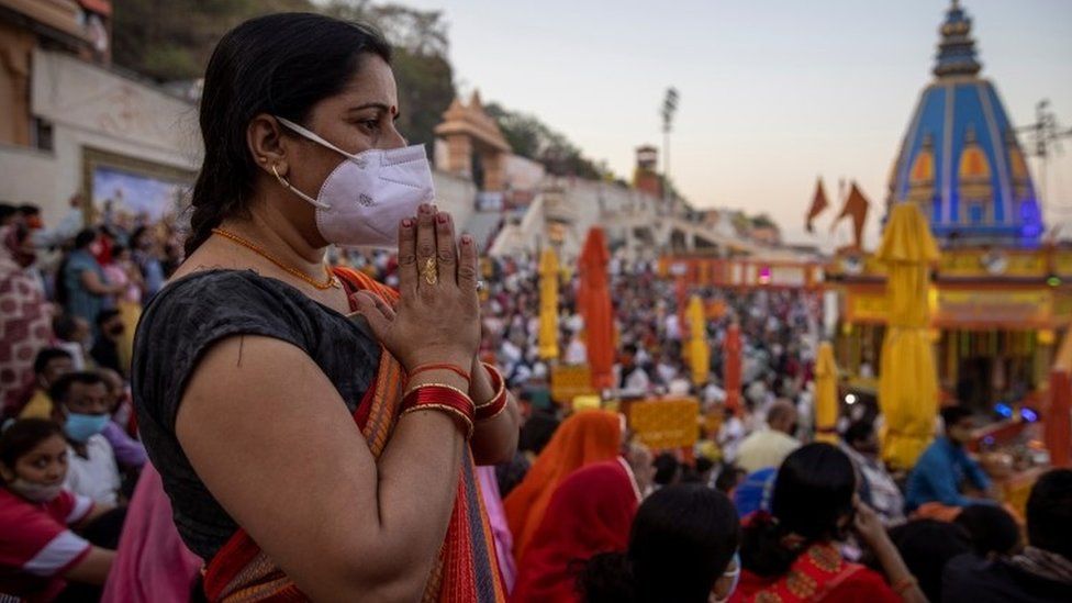 A devotee wearing protective face mask attends an evening prayer on the banks of Ganges river during Kumbh Mela, or the Pitcher Festival, amidst the spread of the coronavirus disease (COVID-19), in Haridwar, India, April 10, 2021.