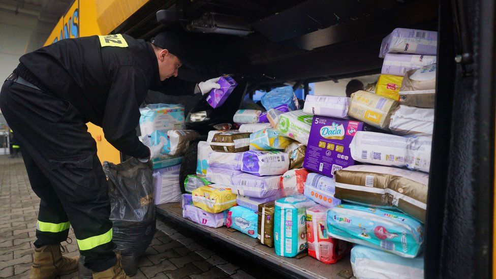 A guard loads aid supplies onto a bus in Przemysl owned by British volunteer Cliff Wilson (left) who will transport it to Ukraine