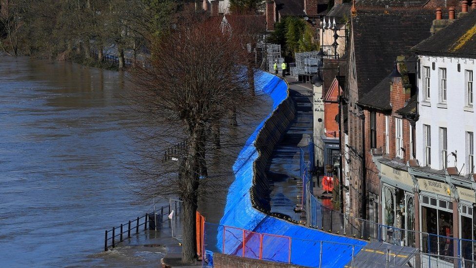 Temporary flood protection barriers are seen in place beside the swollen River Severn at Ironbridge