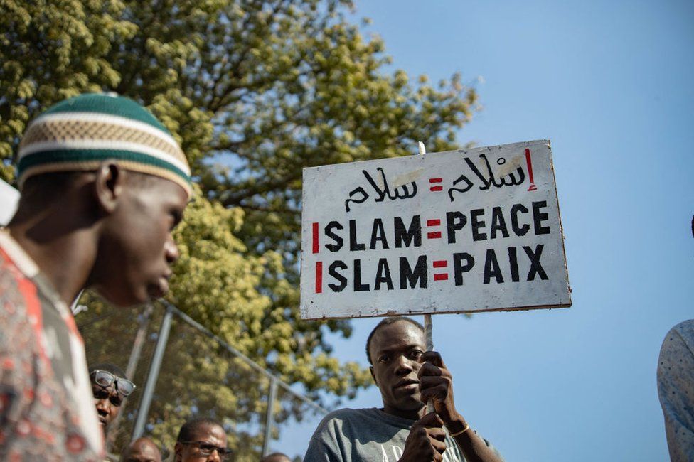 A man holds up a sign "Islam = peace" during an anti-blasphemy protest in Bamako on November 04, 2022, amid High Islamic Council of Mali calls protest after viral video of man "insulting" the Koran.