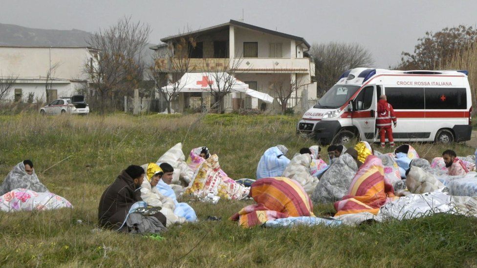 Survivors of a shipwreck off the coast of Calabria huddle in blankets