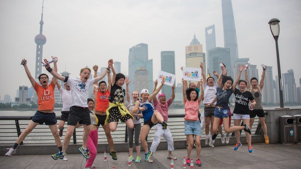 Participants of the ShanghaiPRIDE run pose for pictures during a break on the Bund in front of the financial district of Pudong in Shanghai on June 13, 2015