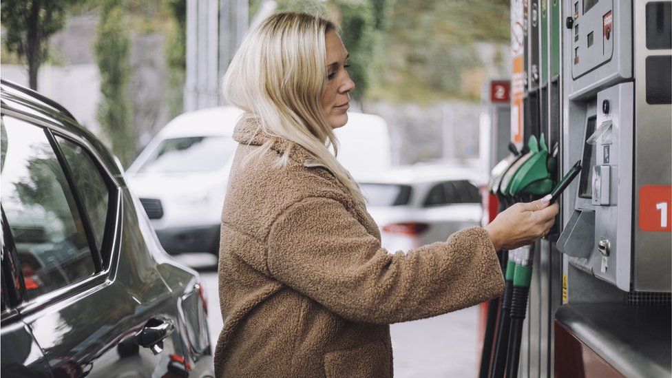Женщина платит за бензин на заправке