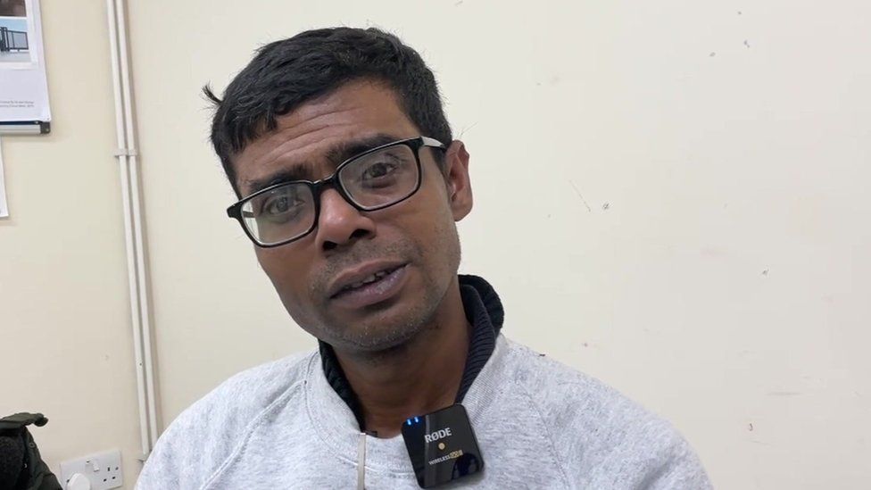 Image of Zubayer Khan in a grey sweatshirt and glasses.