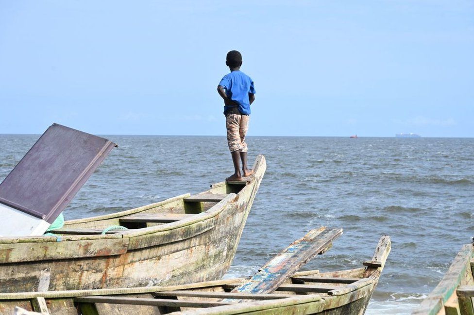A boy stands on an artisanal fisherman's canoe at the Port-Bouet beach in Abidjan.